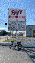 The e-bike locked to the donut shop sign.